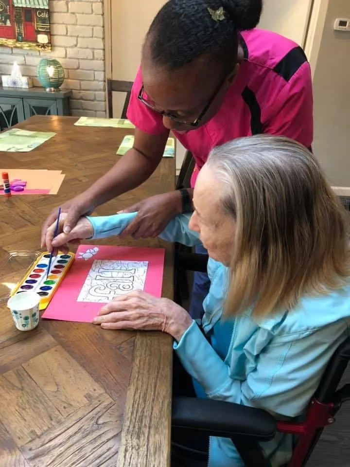 A caregiver helping a resident with a painting in Dallas